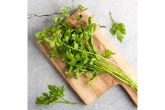 Parsley leaves on a brown cutting board.